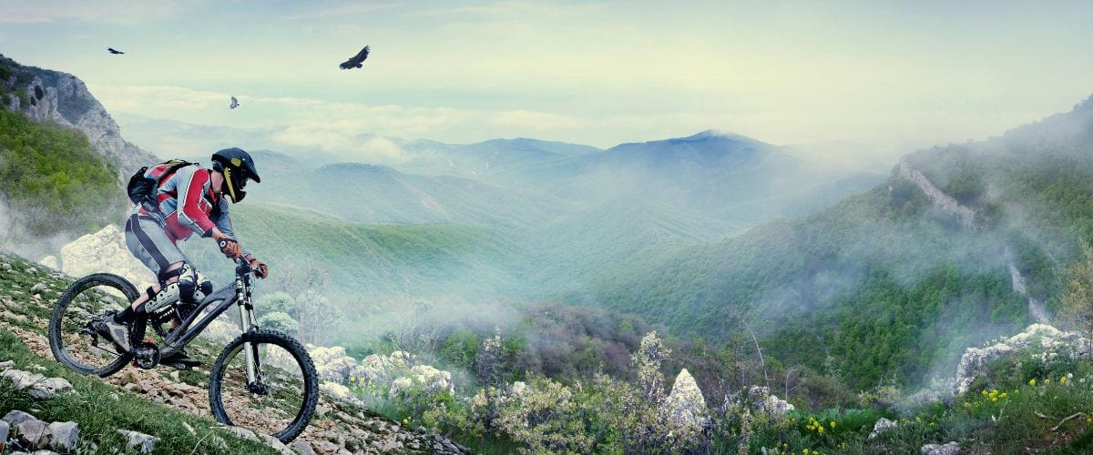 Solo Mountain Biker On The Mountain Trail With Eagles Soaring High above